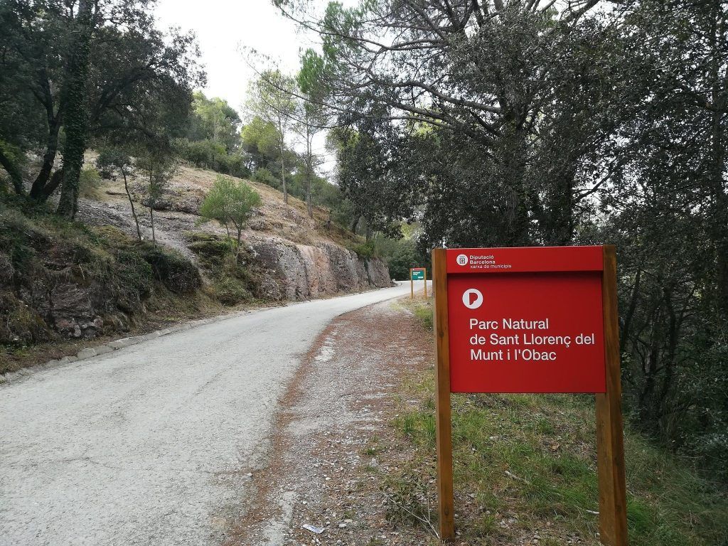 Camino forestal con una señal de entrada al parque natural