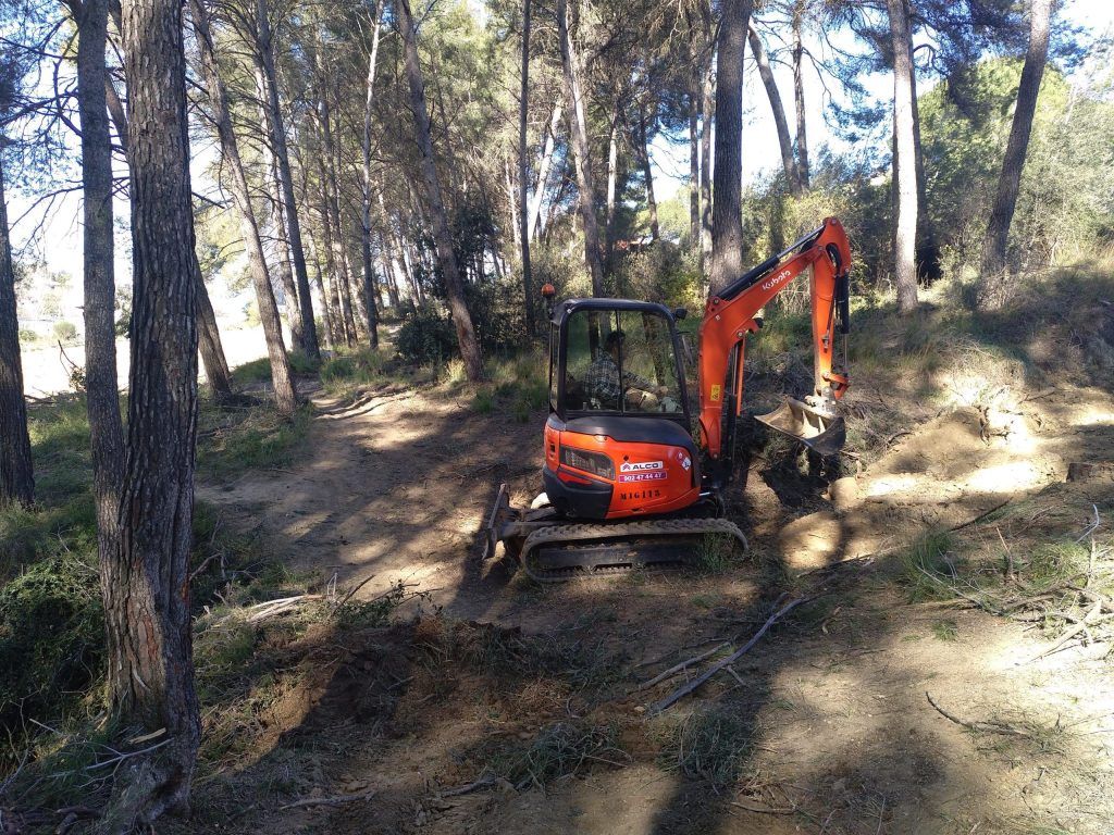 Minigiratoria trabajando y moviendo tierras en una pista forestal